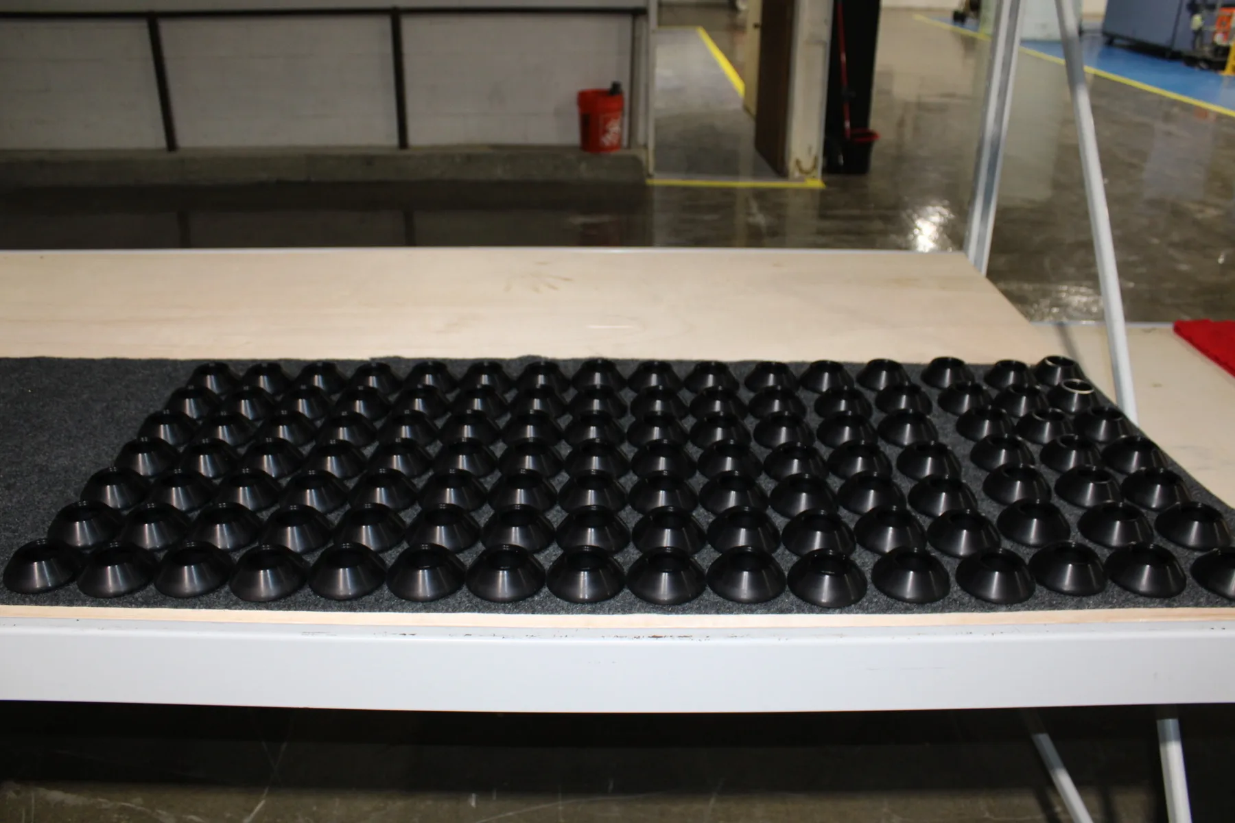 Rows of dark finished parts laid out on the bench at AnoPRO