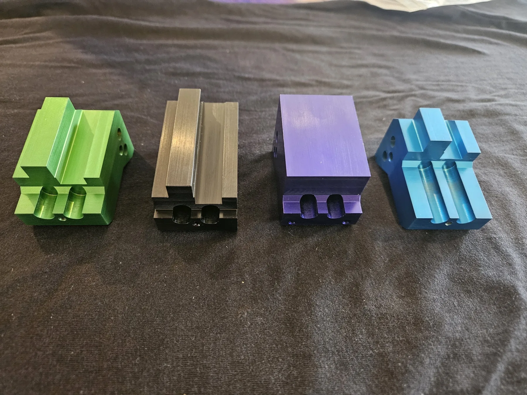 Anodized fixture blocks in green, gray, purple, and blue machined for a customer