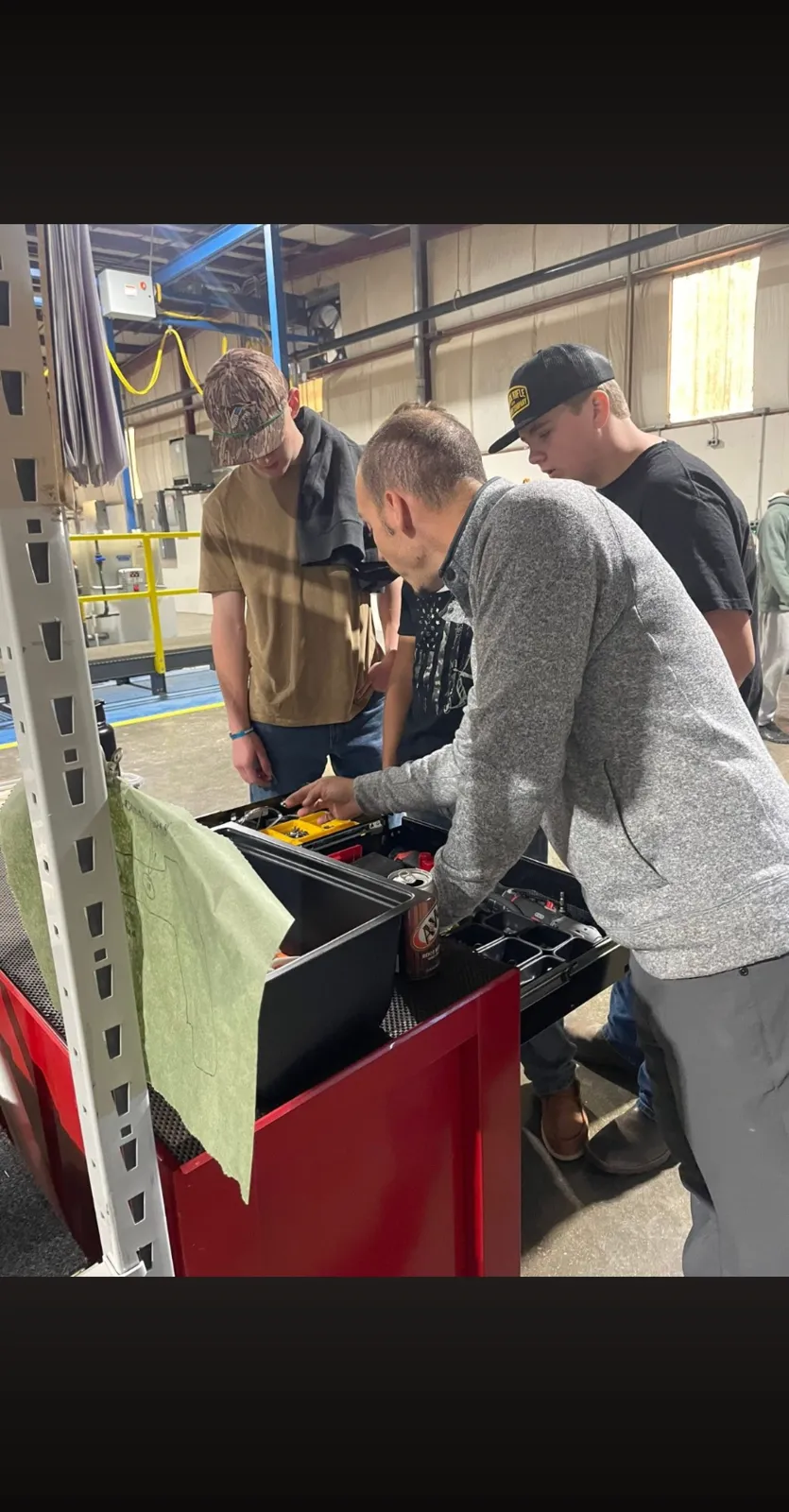 A mentor and students examining tooling during a workshop event at the plant