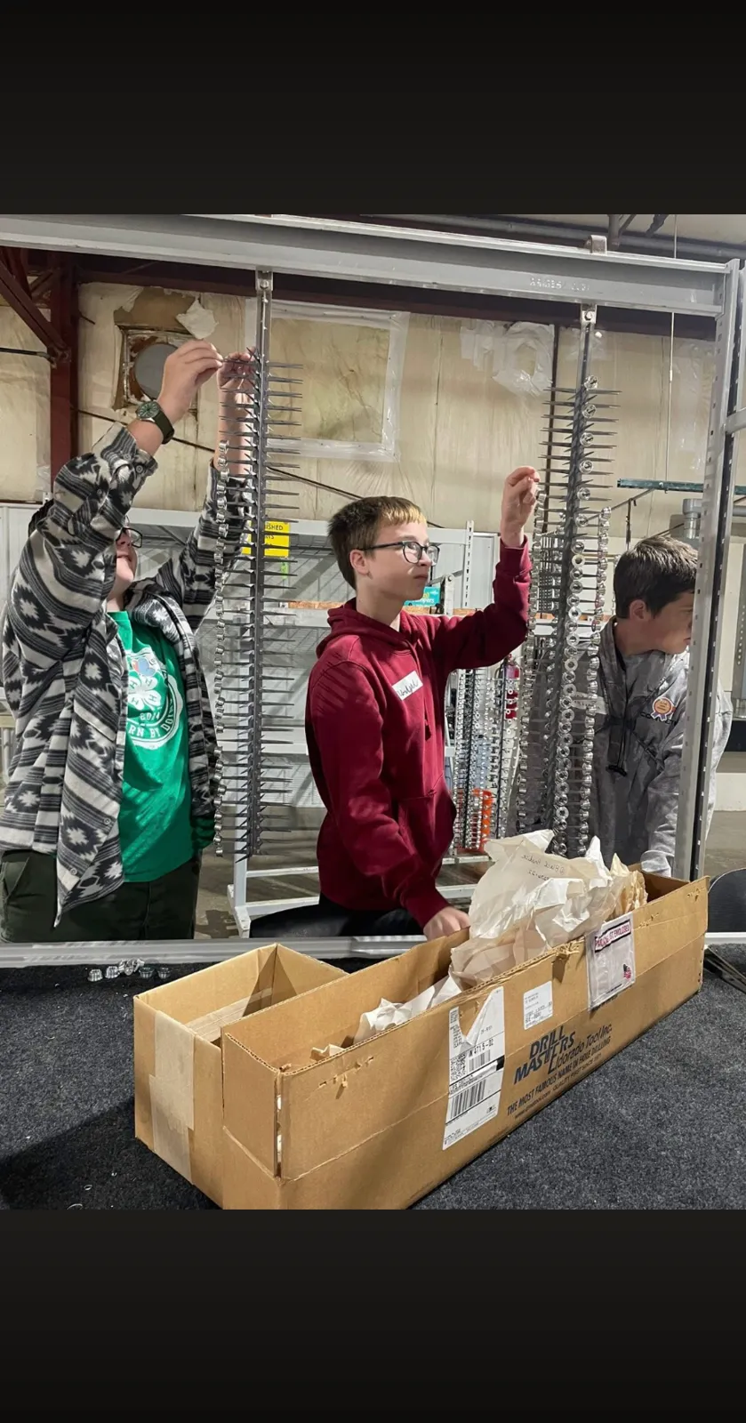 Students hanging small parts on anodizing racks during a plant event