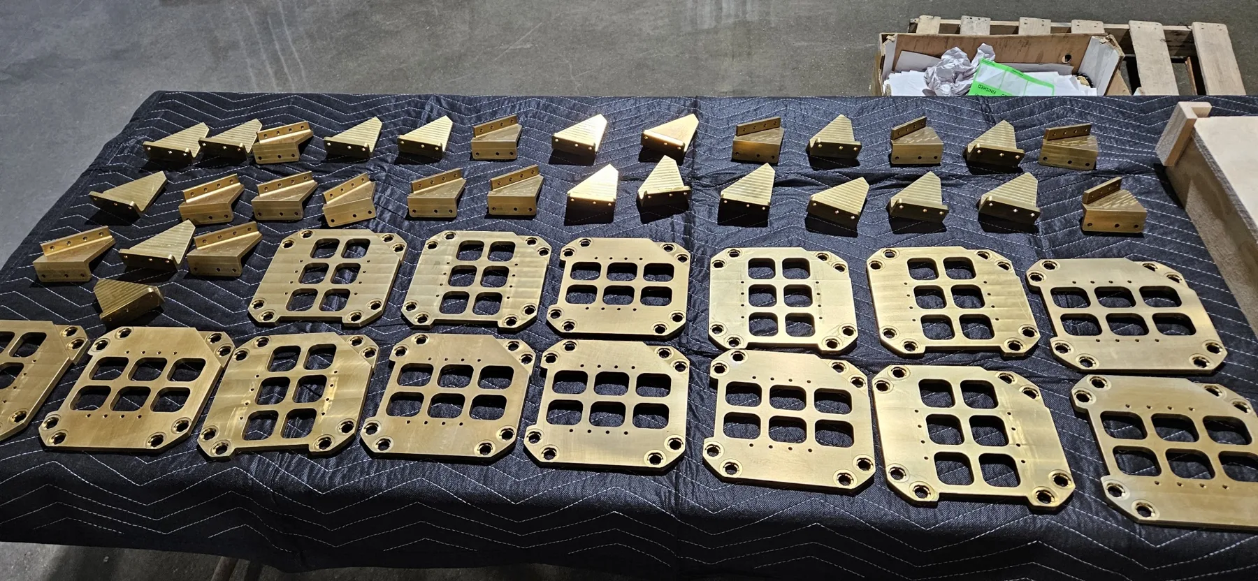 Gold anodized manifold plates and brackets laid out after finishing