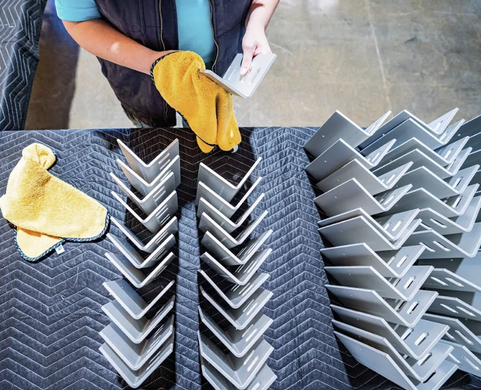 Gloved worker inspecting finished clear anodized angle brackets